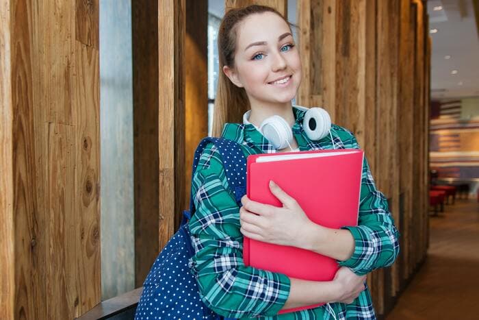 Student standing in front of a college library, ready to learn how to make a writing portfolio for college